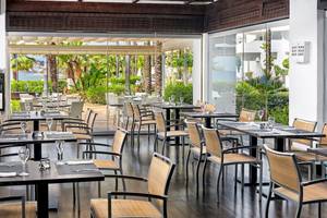 Innenansicht des Restaurants im H10 Estepona Palace mit Blick auf den Garten und das Meer.