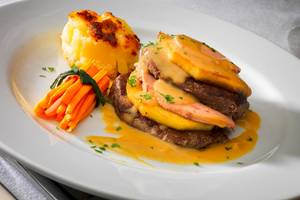 Ein Gericht auf einem weißen Teller, bestehend aus Steak, Kartoffelpüree und Karotten.