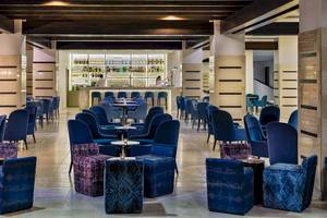 Innenbereich des H10 Estepona Palace Hotels mit Bar und blauen Stühlen.
