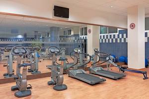 Fitnesscenter im H10 Estepona Palace mit Laufbändern, Rudergeräten und Hanteln.