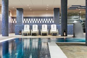 Innenpool des H10 Estepona Palace mit weißen Liegen und blauen Säulen
