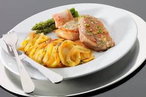 Gericht auf einem weißen Teller im H10 Estepona Palast Hotel mit Fleisch, Gemüse und Beilagen.