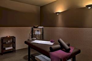 Massageraum im H10 Estepona Palace Hotel mit Liege, Kissen, Handtüchern und Dekoartikeln.