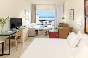 Doppelzimmer im H10 Estepona Palace mit Meerblick, inklusive Wohnzimmer, zwei Betten, Balkon und Fernseher.