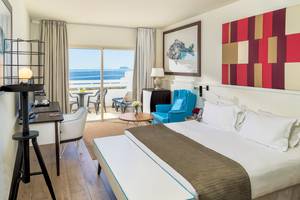 Innenansicht eines Hotelzimmers im H10 Estepona Palace mit Blick auf das Meer und eine Terrasse.
