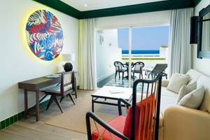 Wohnzimmer des H10 Estepona Palace mit Blick auf das Meer und modernen Möbeln.
