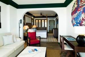 Innenraum der Suite im H10 Estepona Palace mit Wohnzimmer, Esstisch, Schlafzimmer und Dekoration.