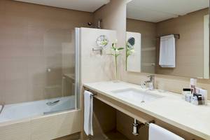 Badezimmer im H10 Estepona Palace mit Badewanne, Waschbecken und Spiegeln.
