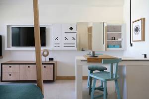 Innenansicht der Suite im Domes Noruz Chania, Autograph Collection mit Fernseher, Essbereich und offenem Badezimmer.