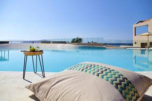 Poolszene im Domes Noruz Chania, Autograph Collection mit Getränken auf einem Tisch und Kissen.