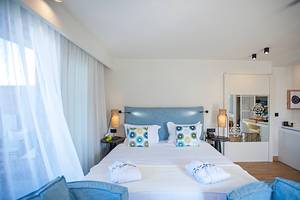 Ein elegantes Hotelzimmer mit einem Doppelbett, zwei Nachttischen und einer gemütlichen Einrichtung im Domes Noruz Chania.