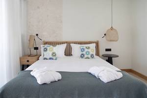 Schlafzimmer im Domes Noruz Chania, Autograph Collection mit weißen Bettwäsche, zwei Nachttischen und dekorativen Lampen.