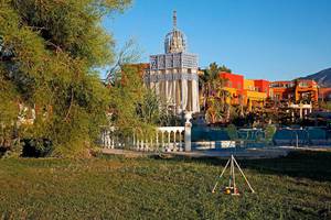 Außenbereich des Orpheas Resorts mit Garten, Spielgeräten und bunten Gebäuden im Hintergrund.