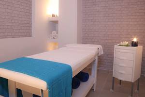 Behandlungsraum im LABRANDA Marine Aquapark Spa mit weißen Wänden, Ziegelmuster und blauen Handtüchern.