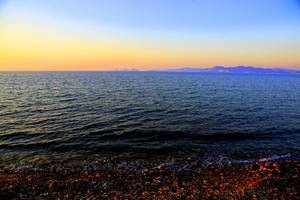 Abendlicher Meerblick mit Felsstrand und ruhigen Wellen am Horizont