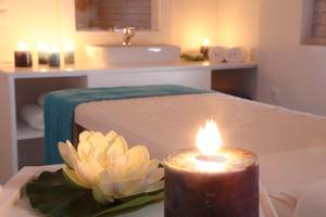 Spa-Behandlungszimmer im LABRANDA Marine Aquapark mit Bett, Kerzen und Lotusblume.