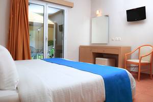 Innenansicht eines Hotelzimmers mit Bett, Nachttisch, Spiegel und Fernseher.