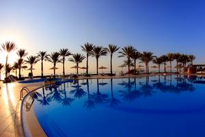 Ein Swimmingpool im Sharm Club Beach Resort mit Sonnenuntergang und Palmen