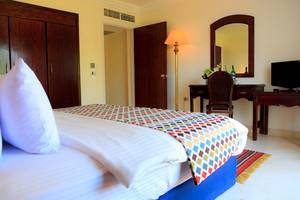 Hotelzimmer im Sharm Club Beach Resort mit Bett, Schreibtisch und Lampe.