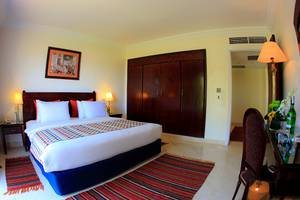 Sharm Club Beach Resort Hotelzimmer mit Bett, Teppichen und Möbeln.