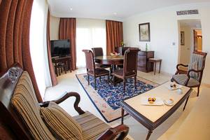 Wohnbereich im Sharm Club Beach Resort mit Tisch, Stühlen, Fernseher und Sofas.