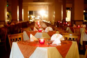 Ein Restaurant im Sharm Club Beach Resort mit gedeckten Tischen, roten Kerzen und dekorativen Lichtern.