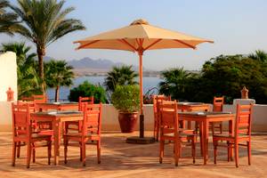 Terrasse im Sharm Club Beach Resort mit Tischen und Stühlen und Blick aufs Meer