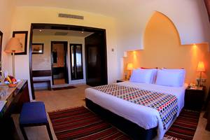 Innenansicht eines Hotelzimmers im Sharm Club Beach Resort mit Doppelbett, Schreibtisch und Dekor