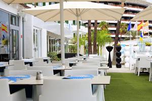 Terrasse des LABRANDA Playa Bonita Hotels mit weißen Tischen und Stühlen unter Sonnenschirmen.