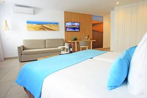 Hotelzimmer im LABRANDA Playa Bonita mit zwei Betten, Sofa, Fernseher und Dekoartikeln.
