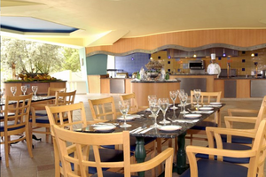 Innenansicht des Restaurants im Dreams Curacao Resort, Spa & Casino mit gedecktem Tisch und Kochbereich.