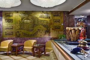 Innenansicht der Lobby des Montecarlo Hotels mit gelben Stühlen, Tischen und einer großen Wandkarte.
