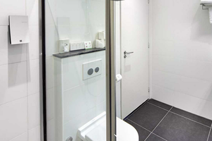 Das Badezimmer im Nova Hotel mit einer Dusche, Toilette, Waschbecken und Fliesenboden.