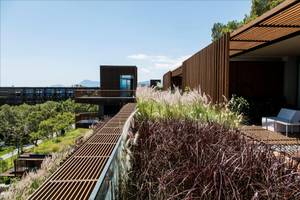 Außenbereich des Maxx Royal Kemer Resorts mit Holzelementen, Pflanzen und Terrassenmöbeln.