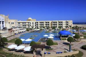 Luftaufnahme des Wyndham Garden Salalah Mirbat Hotels mit Swimmingpools und Liegestühlen.