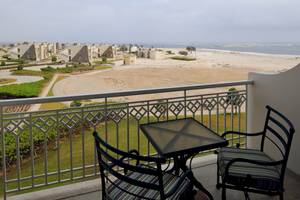 Blick vom Balkon des Wyndham Garden Salalah Mirbat auf eine weite Wüste und das Meer.