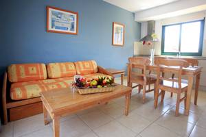 Wohnzimmer im BLUESEA Aloe Corralejo Hotel mit orangefarbener Couch und Tisch mit Obstkorb.