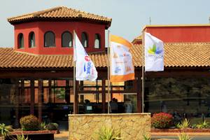 Eingang des Bluesea Aloe Corralejo Hotels mit bunten Flaggen und Gebäuden im Hintergrund.