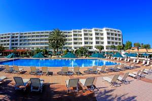 Blue Bay Beach Resort Hotel mit Pool und Liegen, umrandet von Bäumen und Palmen