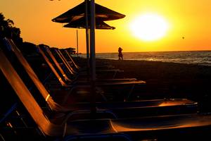 Sonnenuntergang am Strand des Blue Bay Beach Resorts mit einer Person im Vordergrund.