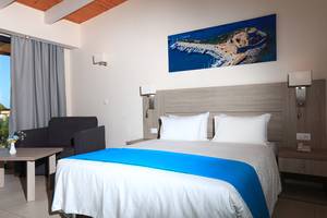 Hotelzimmer im Blue Bay Beach Resort mit Bett, Kissen, und einem Blick auf eine Hafenlandschaft.