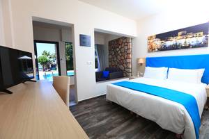 Innenansicht eines Zimmers im Blue Bay Beach Resort mit Bett, Schreibtisch und Fernseher.