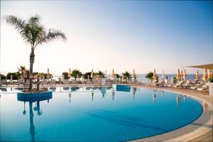 Außenpool des Asterias Beach Hotels mit Sonnenliegen und Sonnenschirmen.