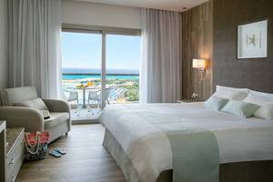 Zimmer im Asterias Beach Hotel mit Blick auf das Meer und einen Balkon.