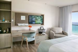 Hotelzimmer im Asterias Beach Hotel mit Bett, Schreibtisch, Stuhl und Fernseher.