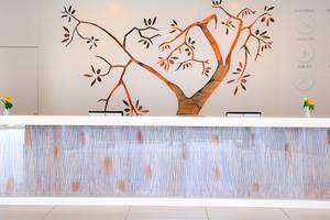 Rezeptionsbereich des Labranda TMT Bodrum mit einer Wandgestaltung, die einen Baum darstellt, und zwei Uhren, die verschiedene Städte darstellen.