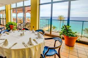Innenansicht des Restaurants des SBH Club Paraiso Playa mit Blick auf das Meer und Palmen.