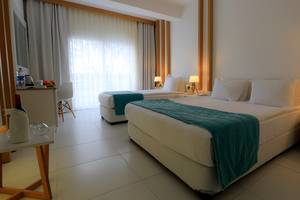 Hotelzimmer im LABRANDA TMT Bodrum mit zwei Betten, weißer Bettwäsche, blauer Decke und modernen Möbeln.