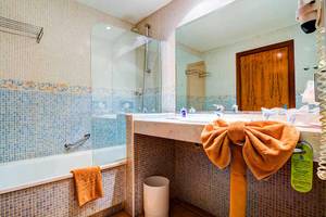 Badezimmer im SBH Club Paraiso Playa Hotel mit blauen Fliesen, Badewanne und Handtüchern.