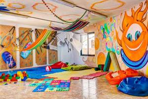 Kinderspielzimmer im SBH Club Paraiso Playa mit bunten Wandmalereien, Hängematten und Spielzeug.